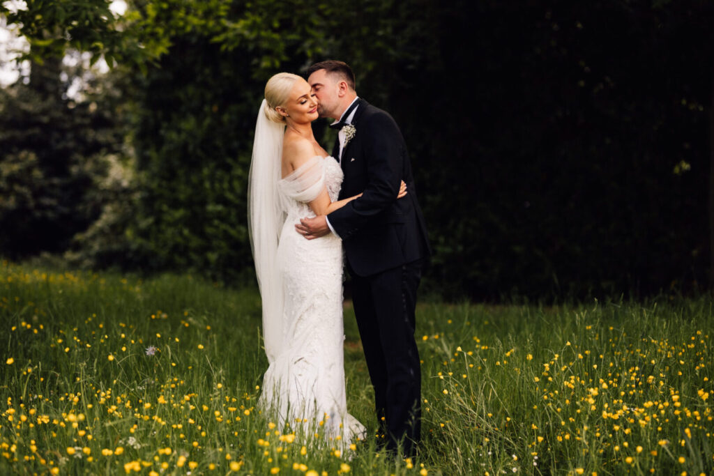 A bride and groom embracing in a field of wildflowers.