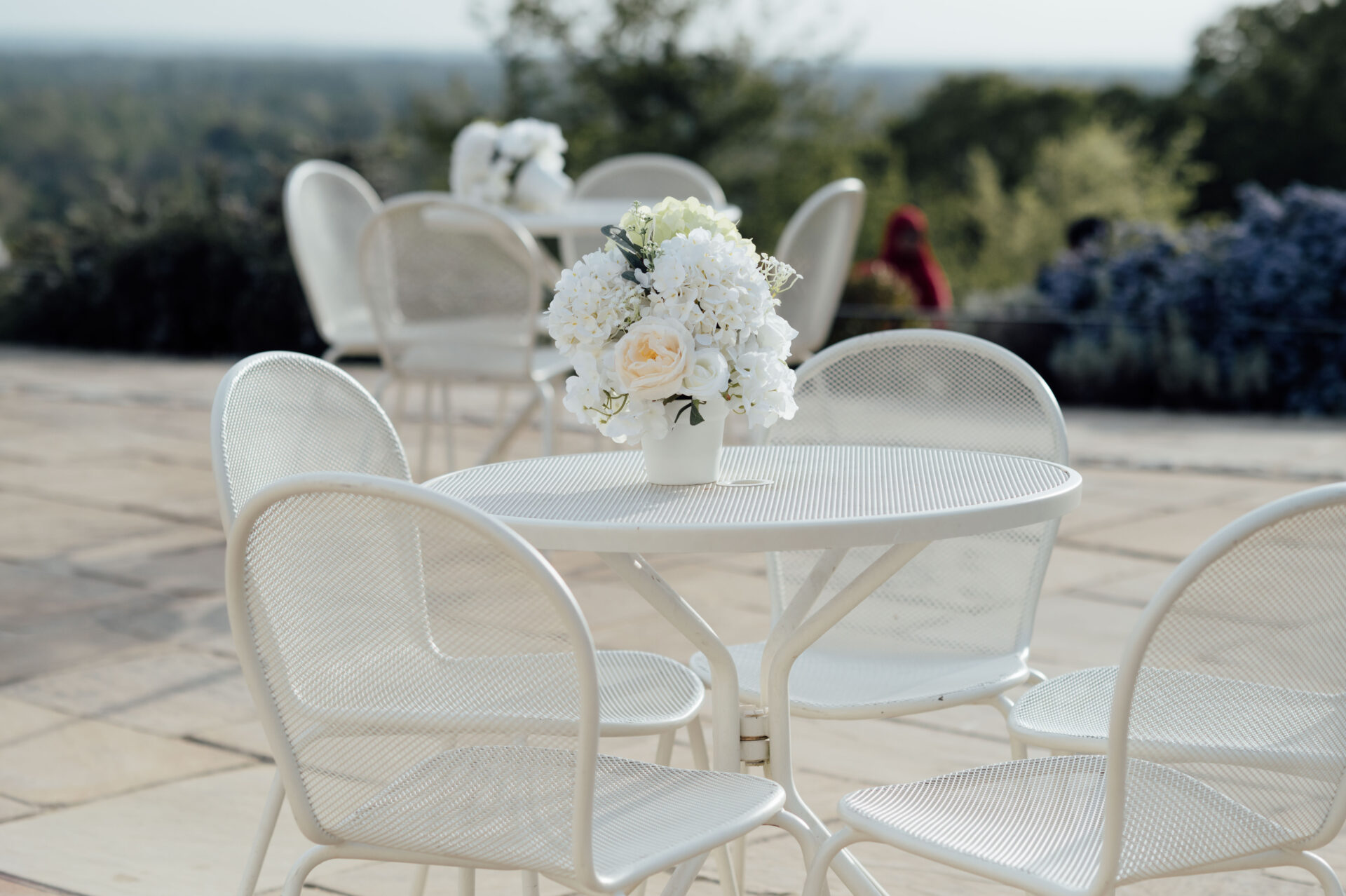 A close up of flowers on a white metal outdoor table.
