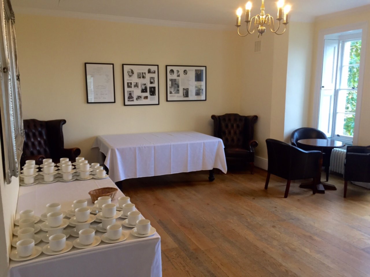 A warm room with tables dressed with white tablecloths and cups and saucers.