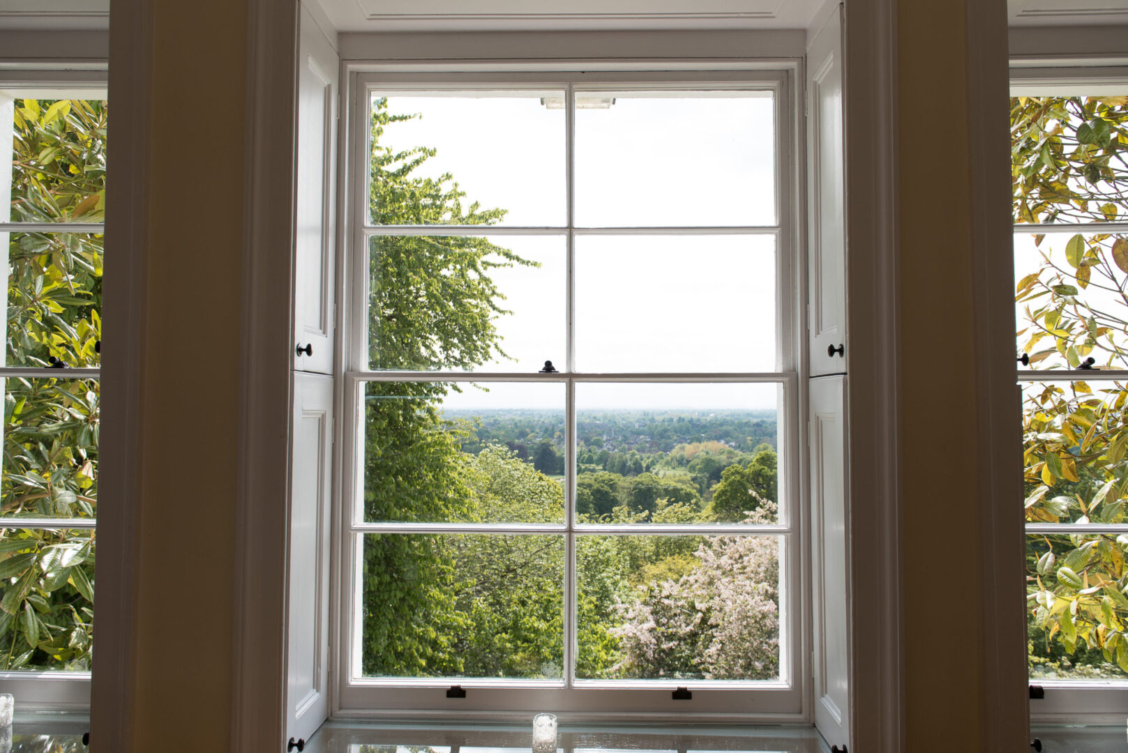 A large white wooden window looking out over parkland.