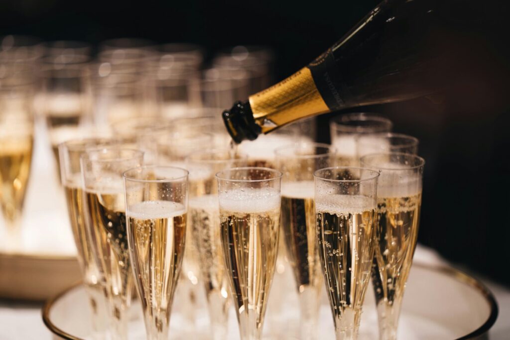 A close up of champagne being poured into tall thin glasses.