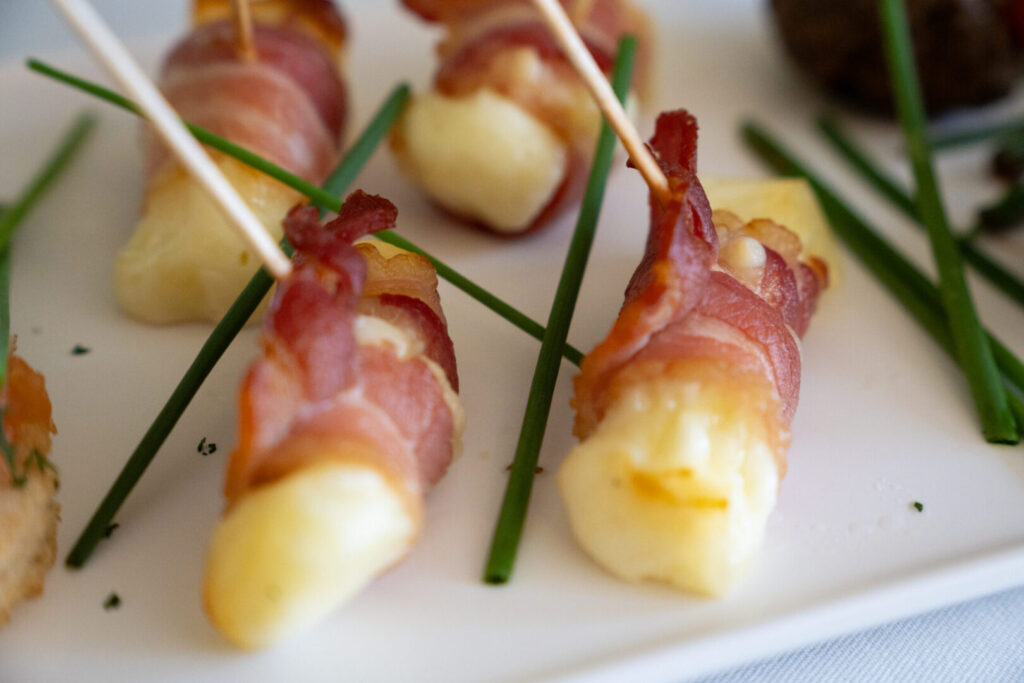 A close up of halloumi strips wrapped in bacon.