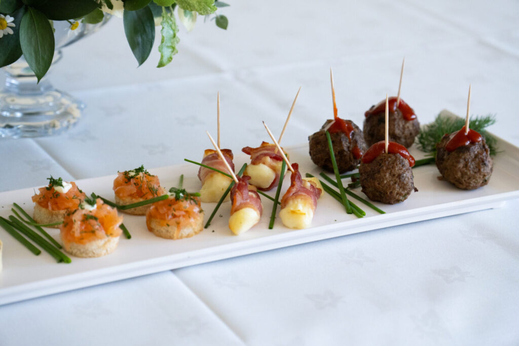 A white square plate with various hors d'oeuvres featuring eggs, cheese and meatballs.