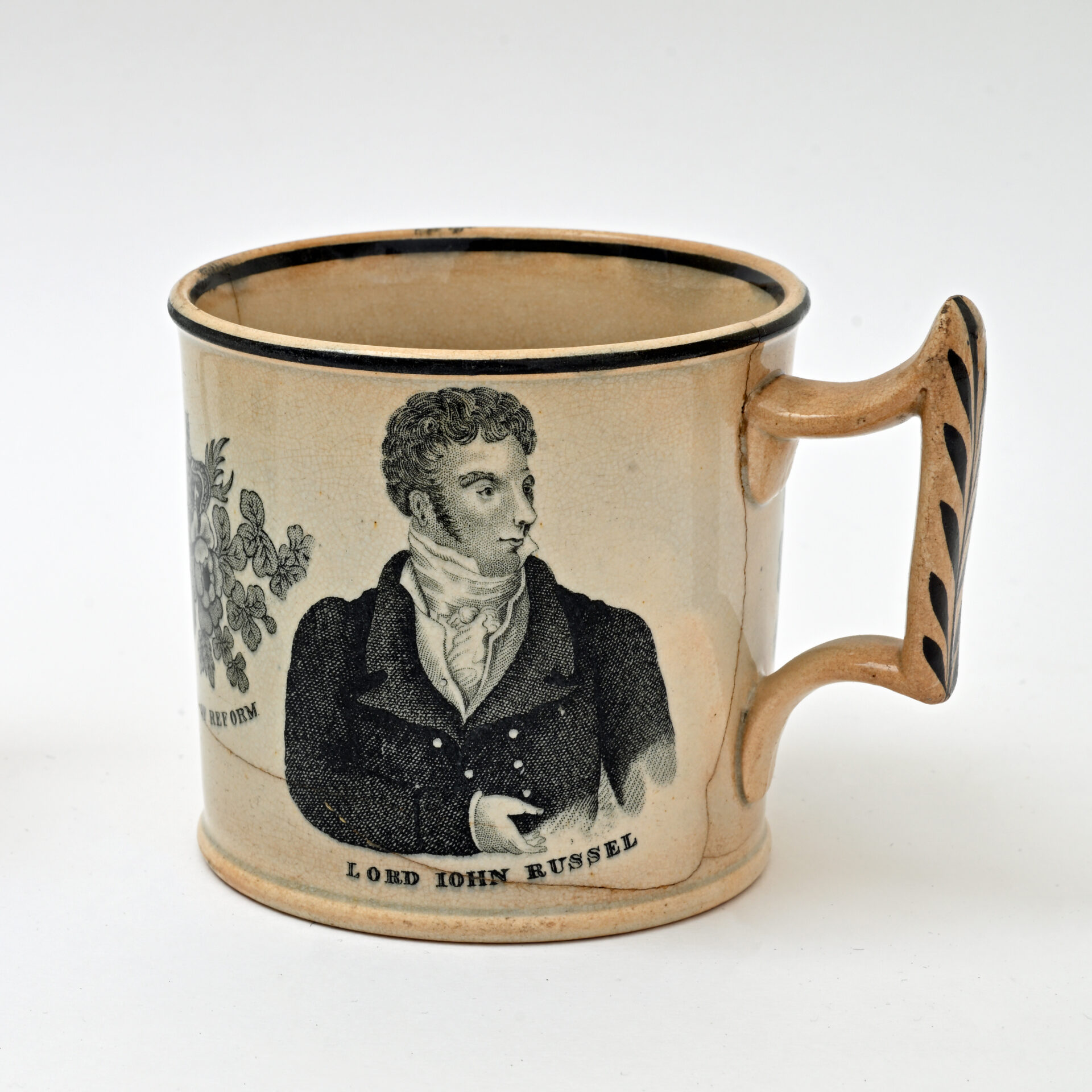 Antique ceramic mug featuring a black-and-white illustration of Lord John Russel in a suit with a cravat, labeled “Lord John Russel.” Decorative floral motif on the left.