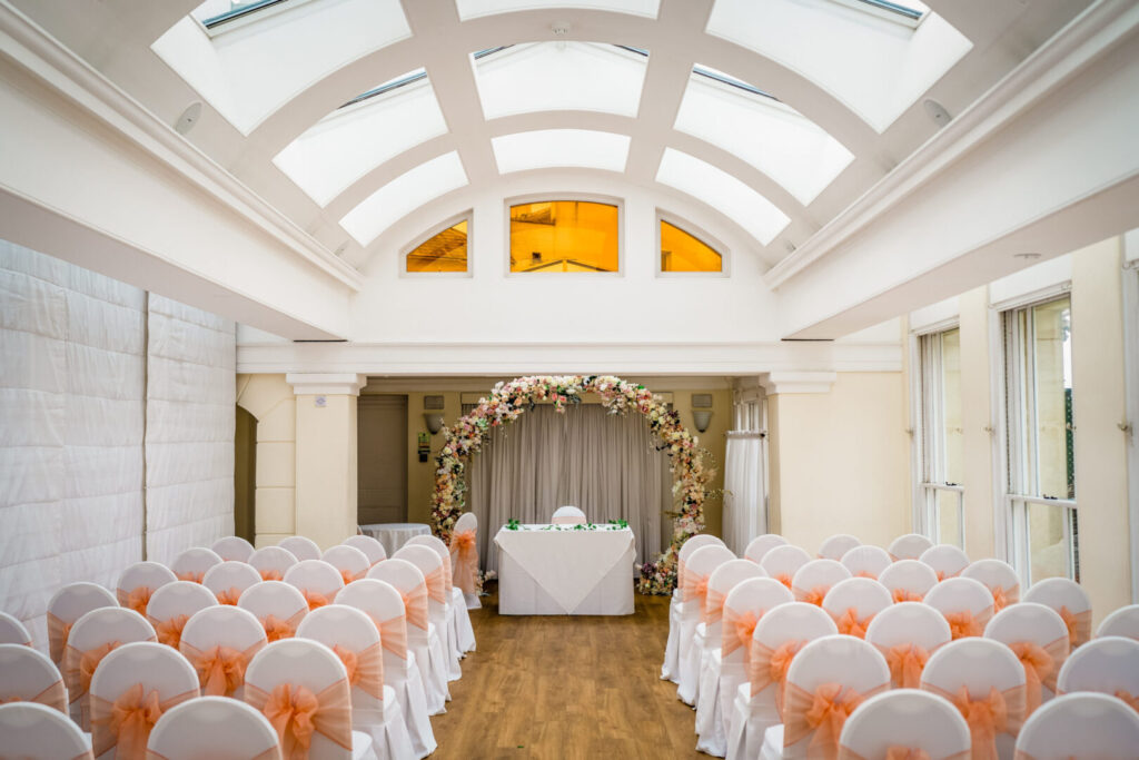 A spacious room with an arched roof and rows of chairs covered in cloth.