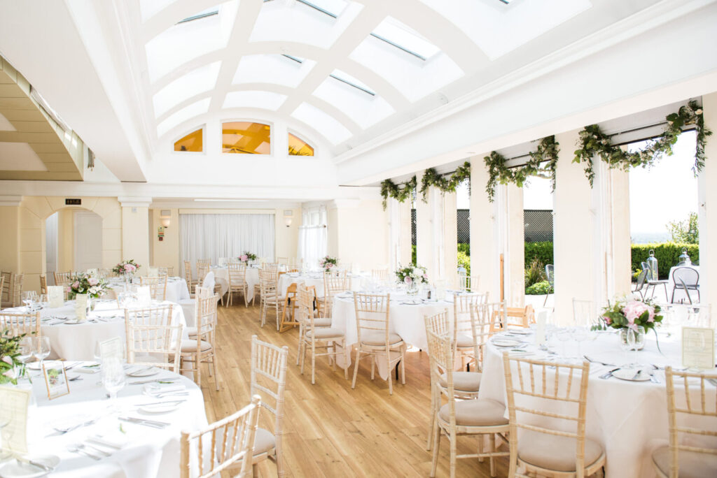 A bright airy room with rows of tables and doorways framed by flowers.