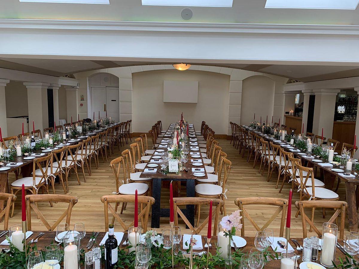 A long wedding reception table elegantly set with white linens, floral centerpieces, and place settings for guests.