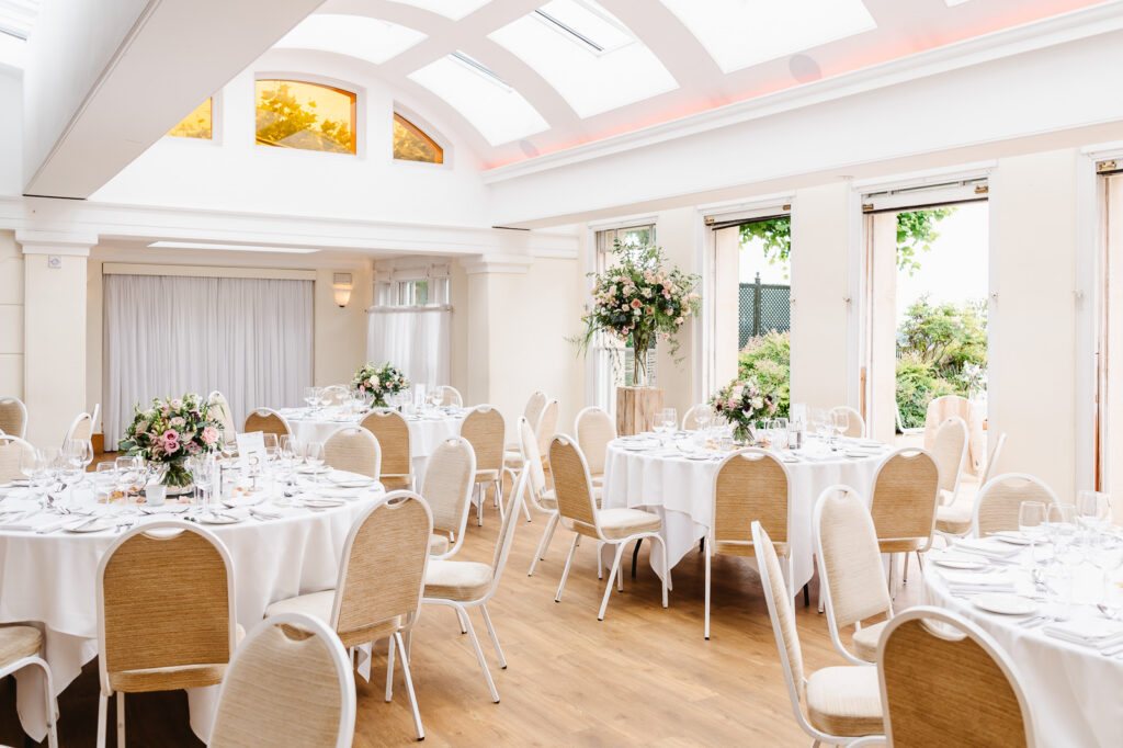 A bright room with an arched room, open doors and tables with white tablecloths.