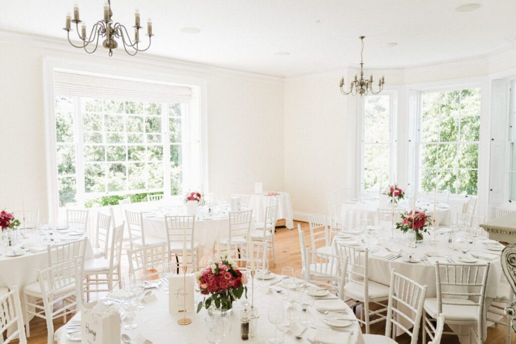 A wedding reception space with tables draped in white tablecloths.
