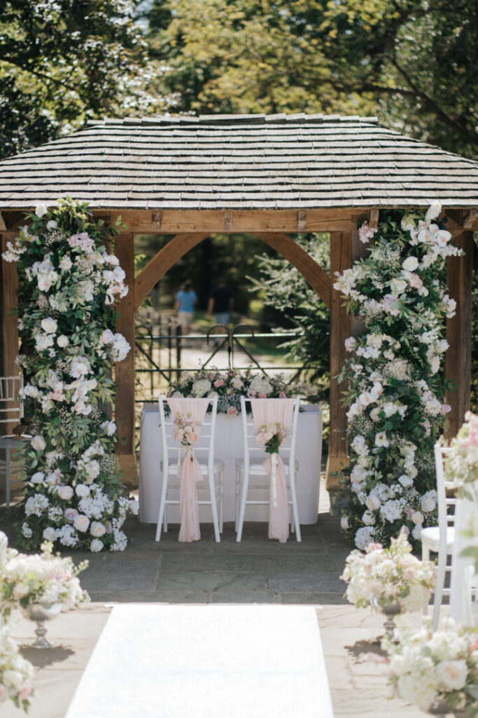 A park setting for a wedding ceremony, showcasing a floral arch.