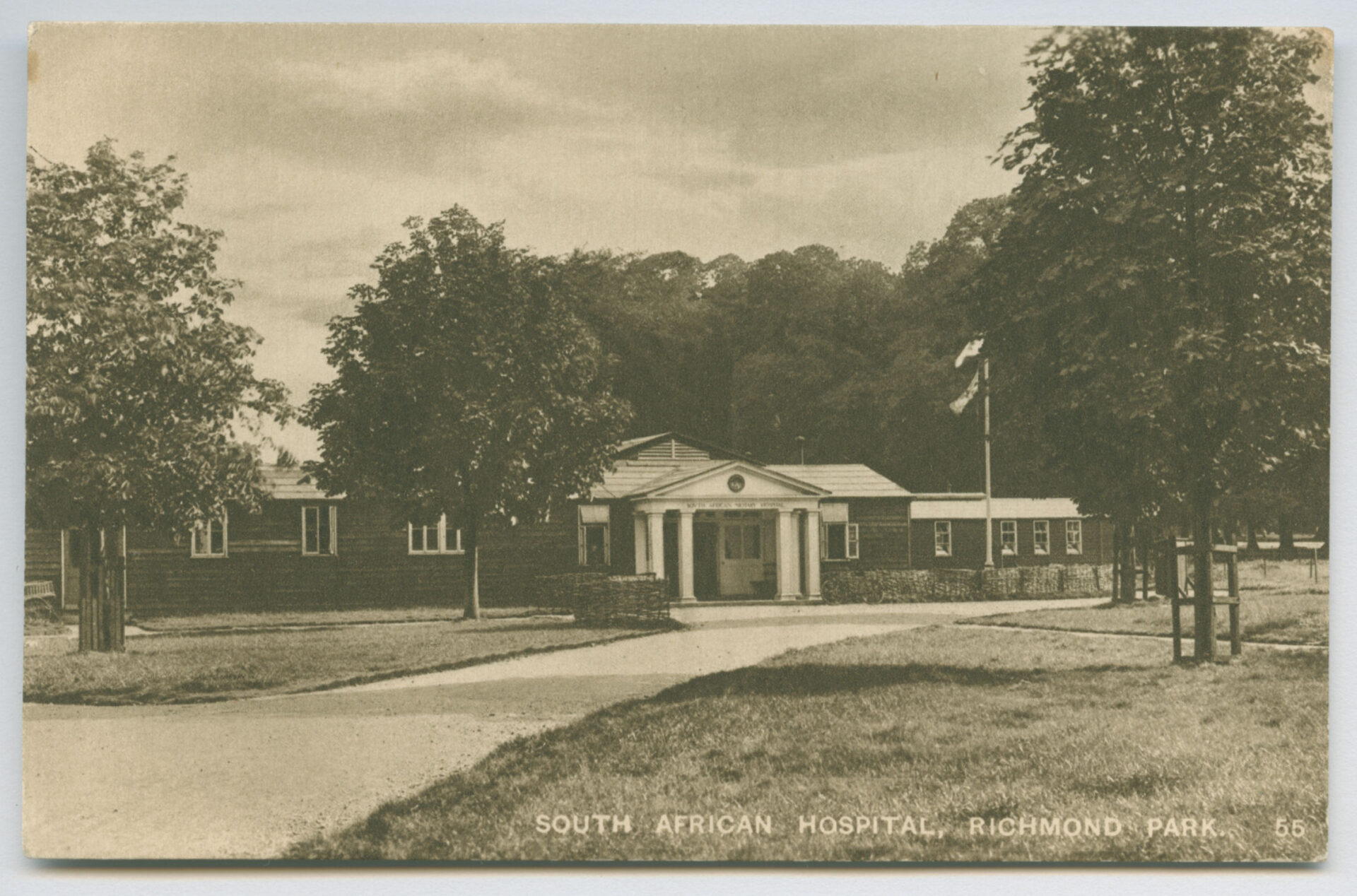 Historic sepia-toned photo of South African Hospital in Richmond Park, with a tree-lined path leading to the entrance, conveying a tranquil atmosphere.