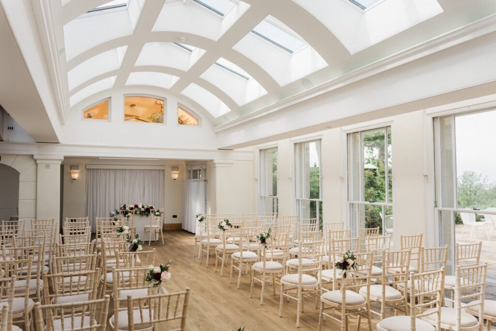An ornate wedding venue room with rows of minimal chairs.