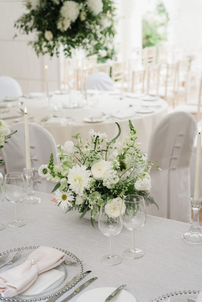 A white floral arrangement on a laid table.