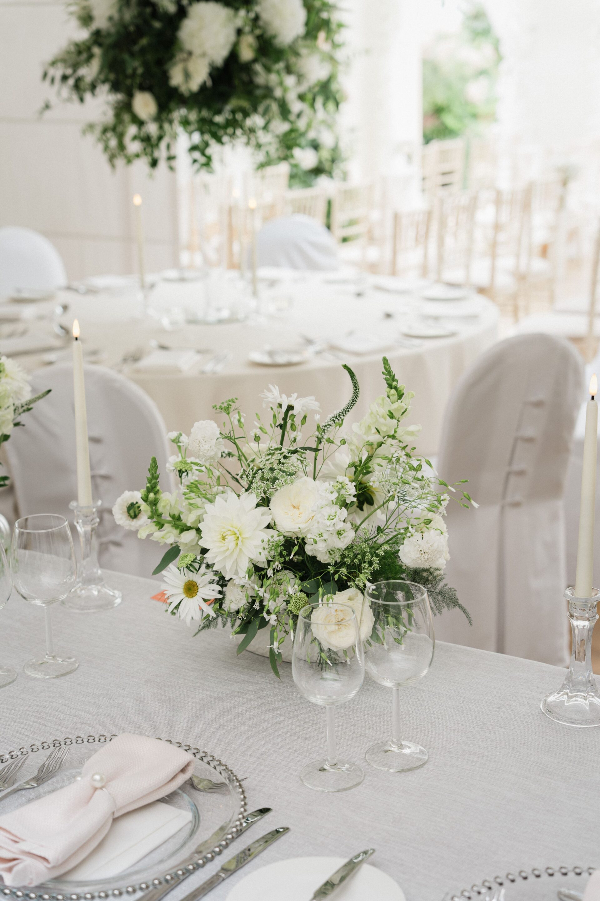 A white floral arrangement on a laid table.