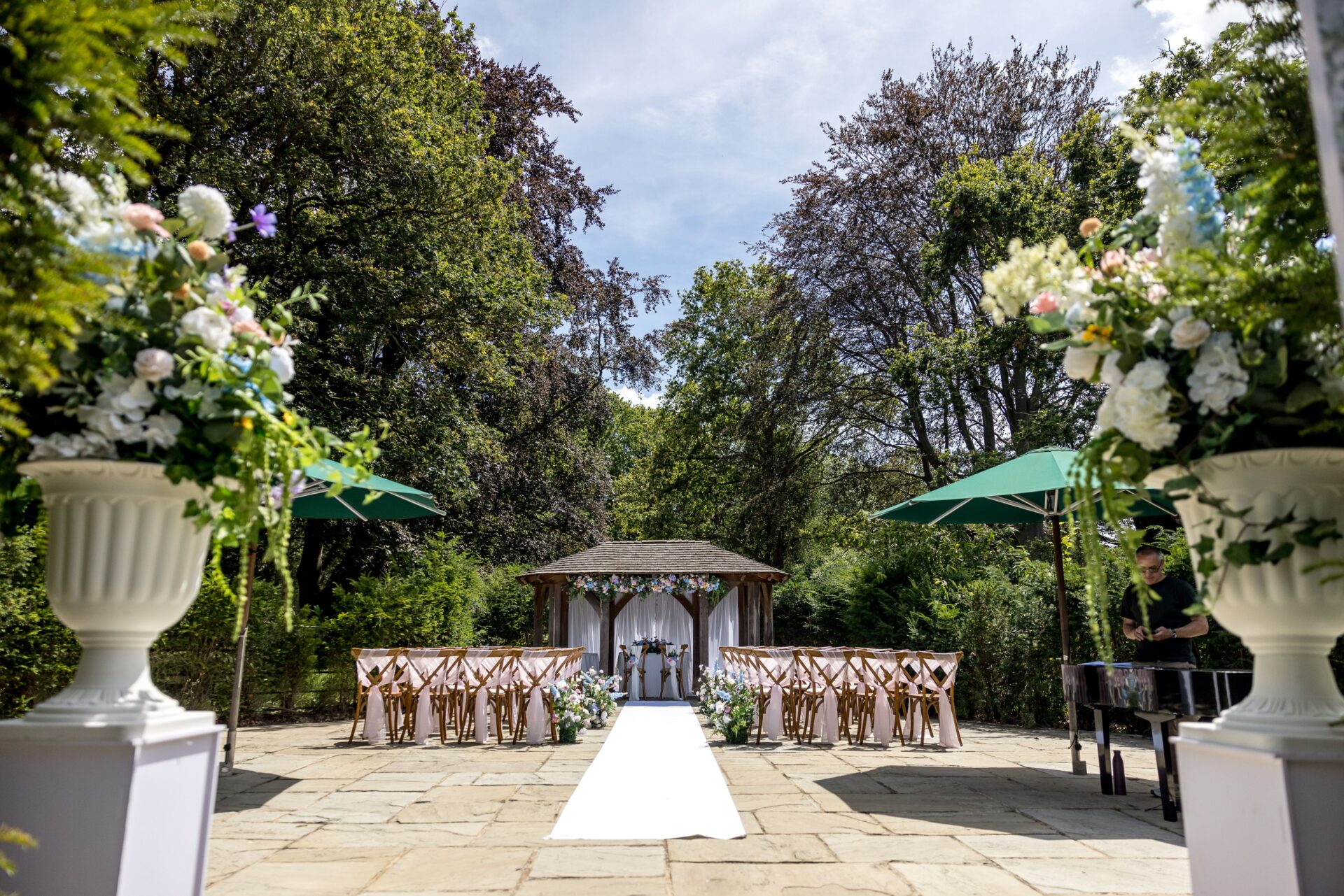 A large patio with a wooden arch and rows of chairs.