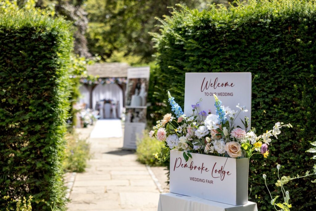 A wedding welcome sign next to a secluded garden area.