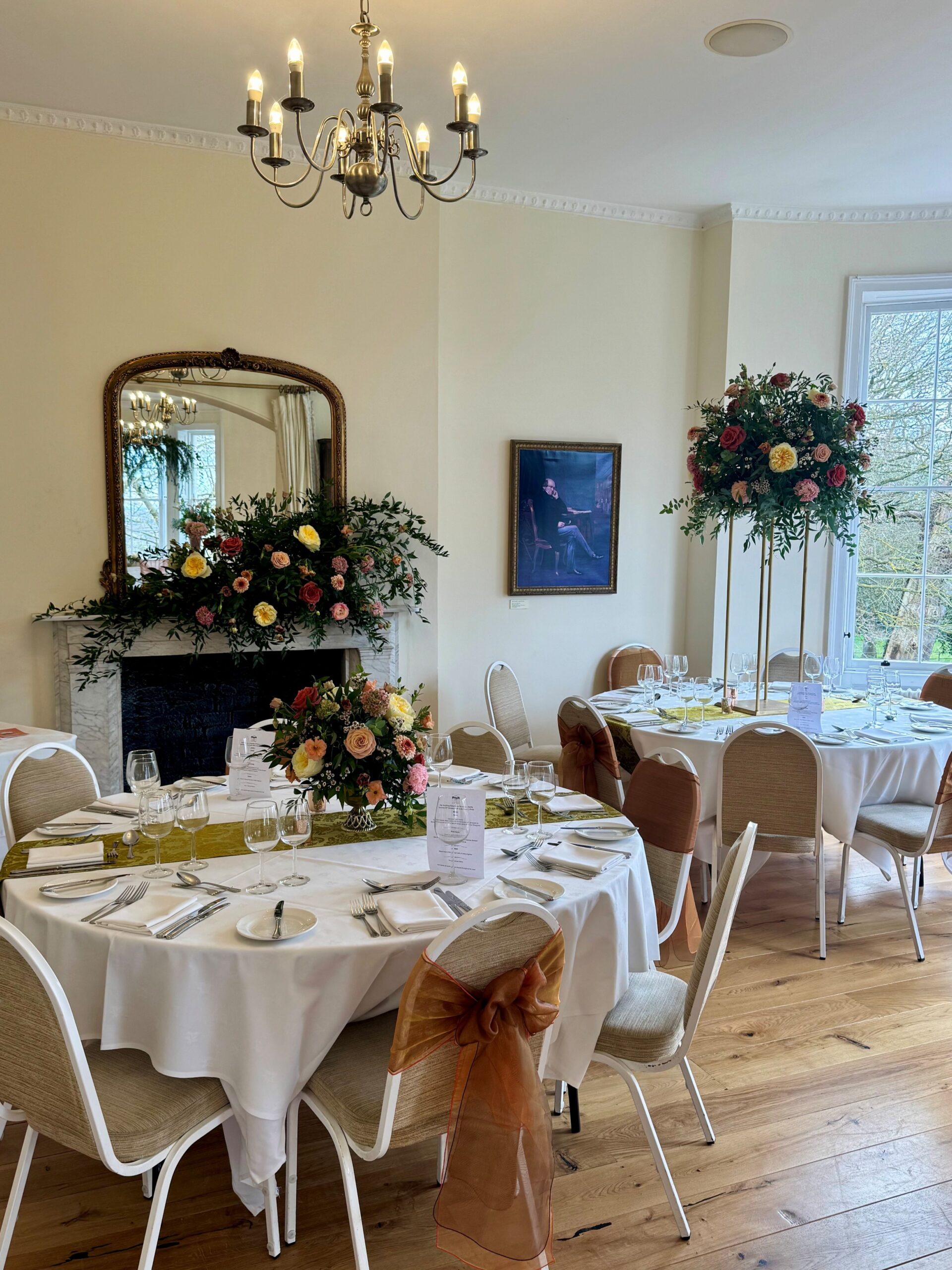 A bright room with a fireplace and round tables set.