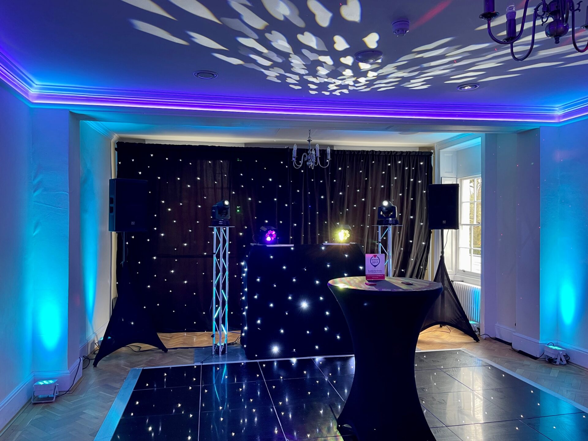 A large room with a DJ booth and a dance floor.