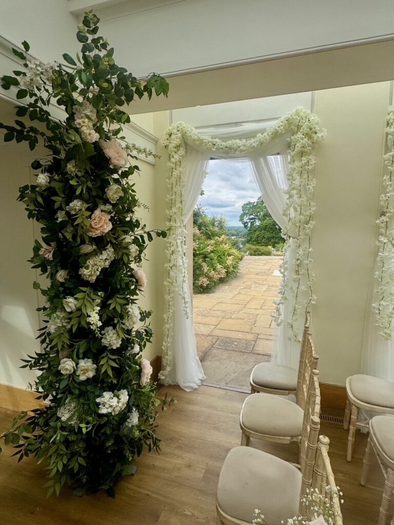 A floral archway with chairs and an open doorway.