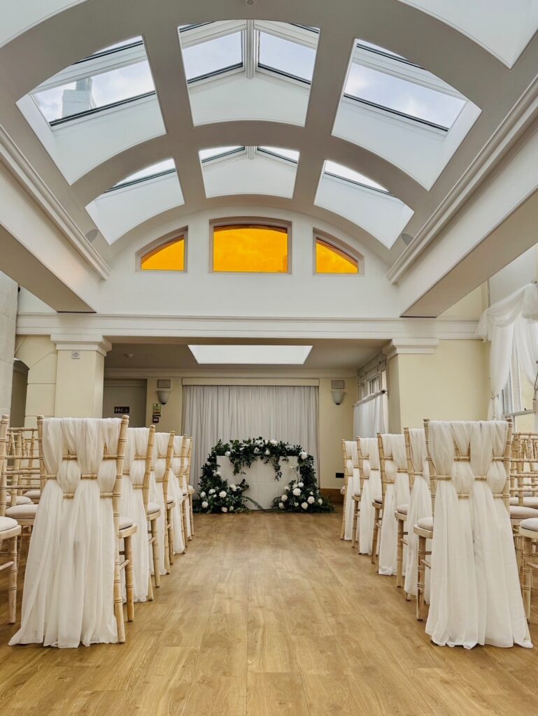 Rows of chairs with white material in an ornate room.