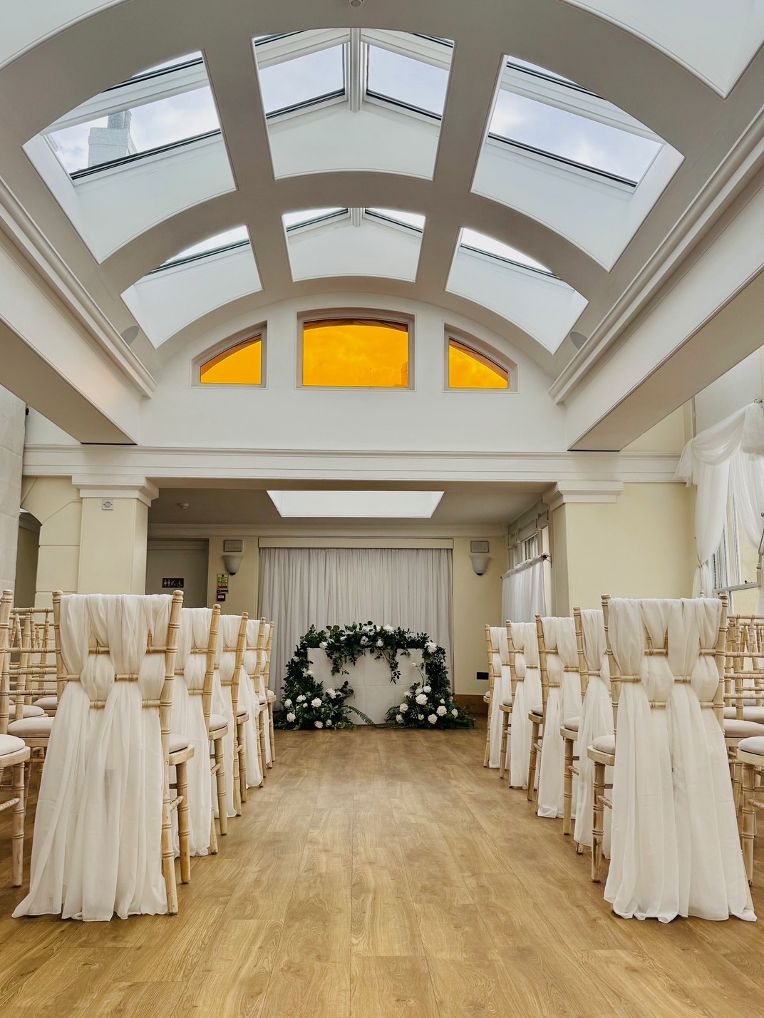 Rows of chairs with white material in an ornate room.