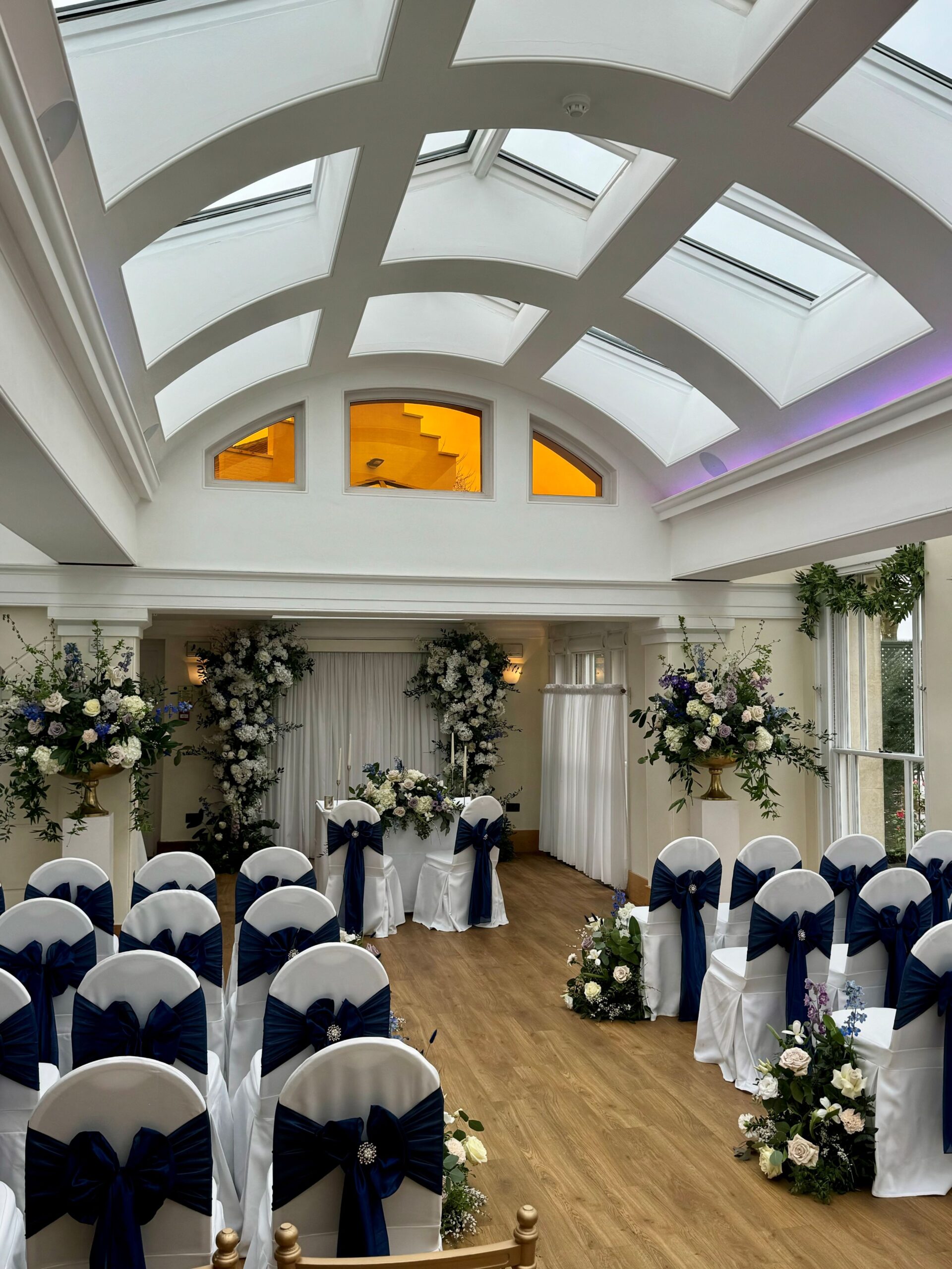 A wedding ceremony set up with dark colours in a large room.