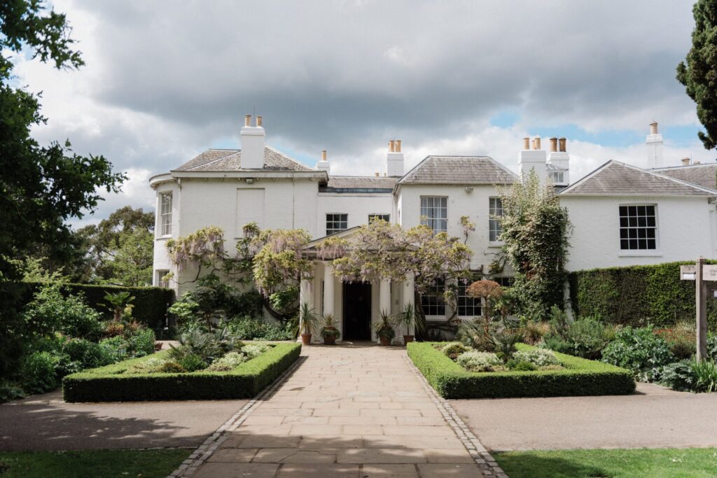 An ornate Georgian building with green hedges and Wisteria.