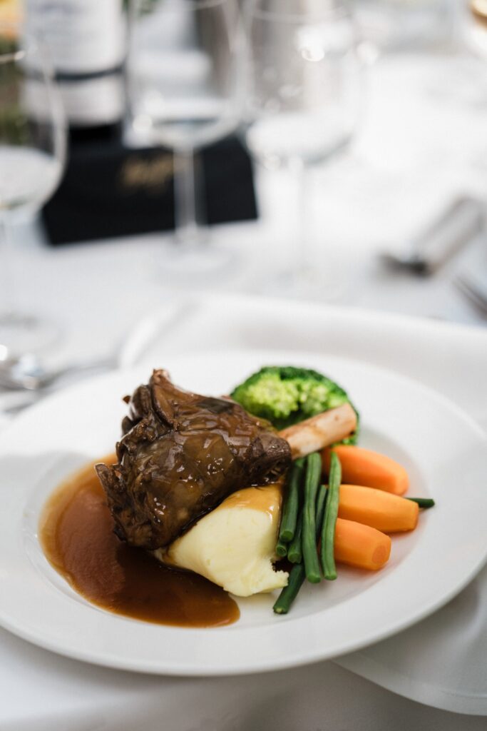 A close up of a lamb shank on a white plate.