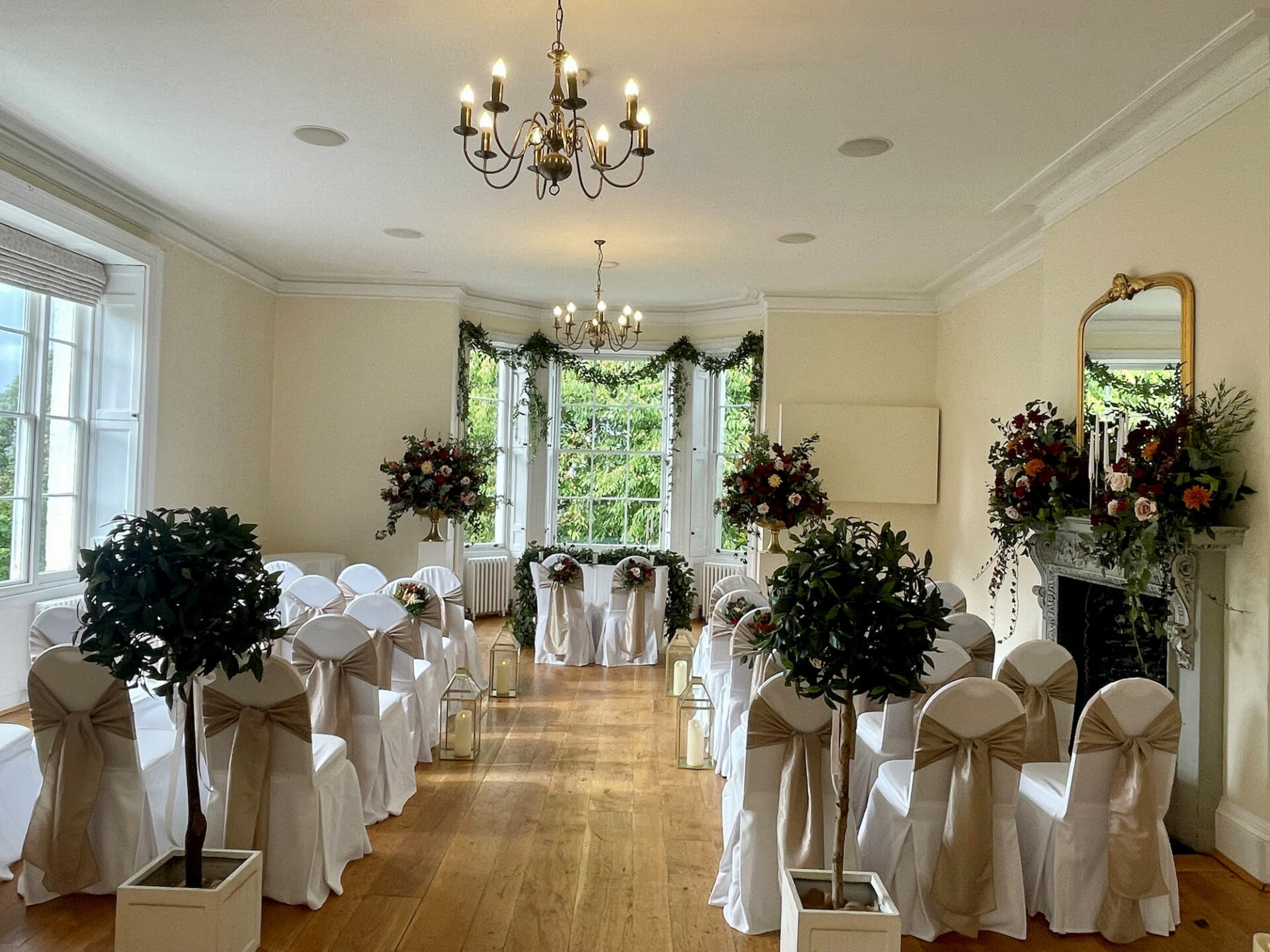 A wedding ceremony room featuring white chairs arranged neatly and adorned with floral decorations.